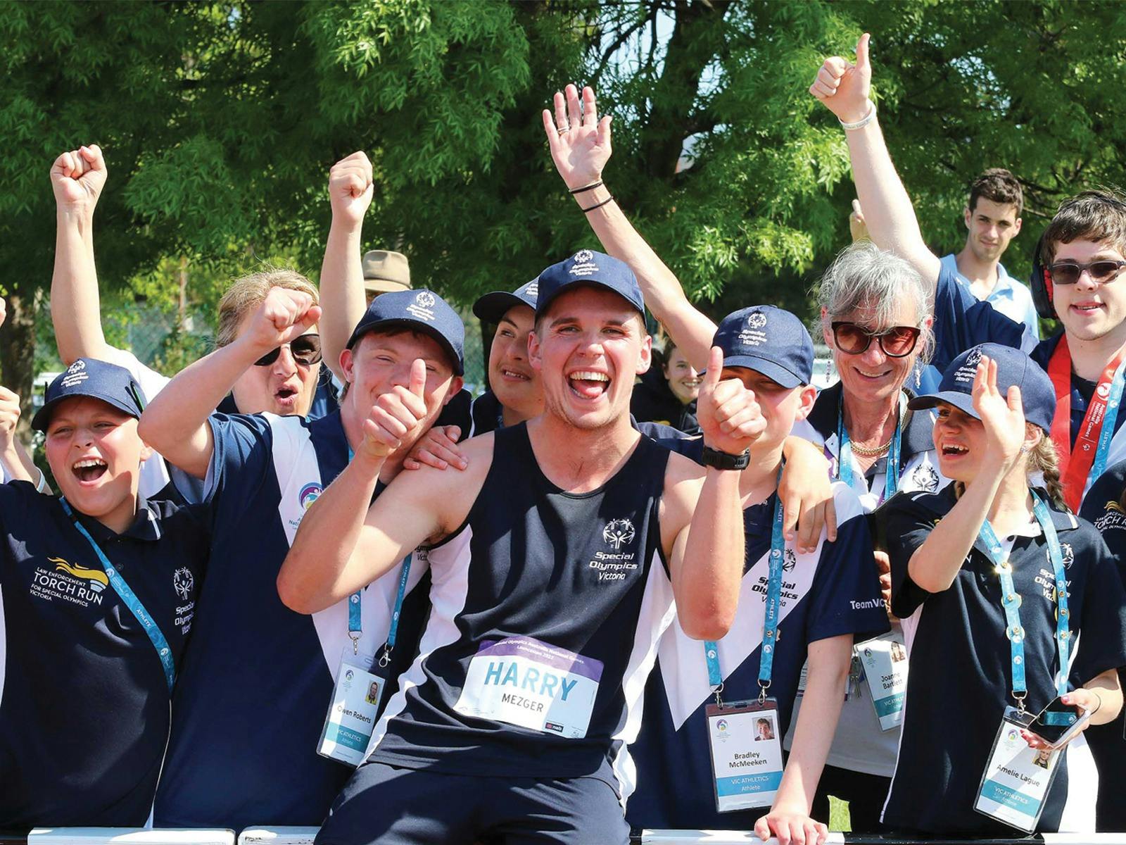 A group of athletes dressed in Team Victoria uniforms celebrate together