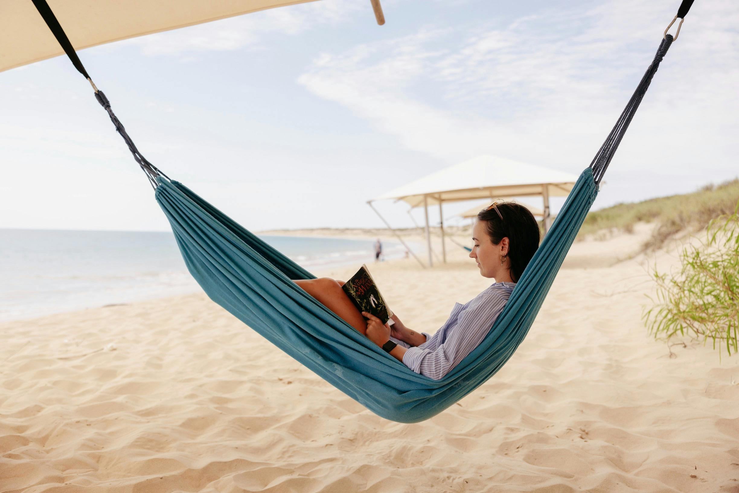 Person reading in a hammock on the beach at Eco Beach Resort in Broome