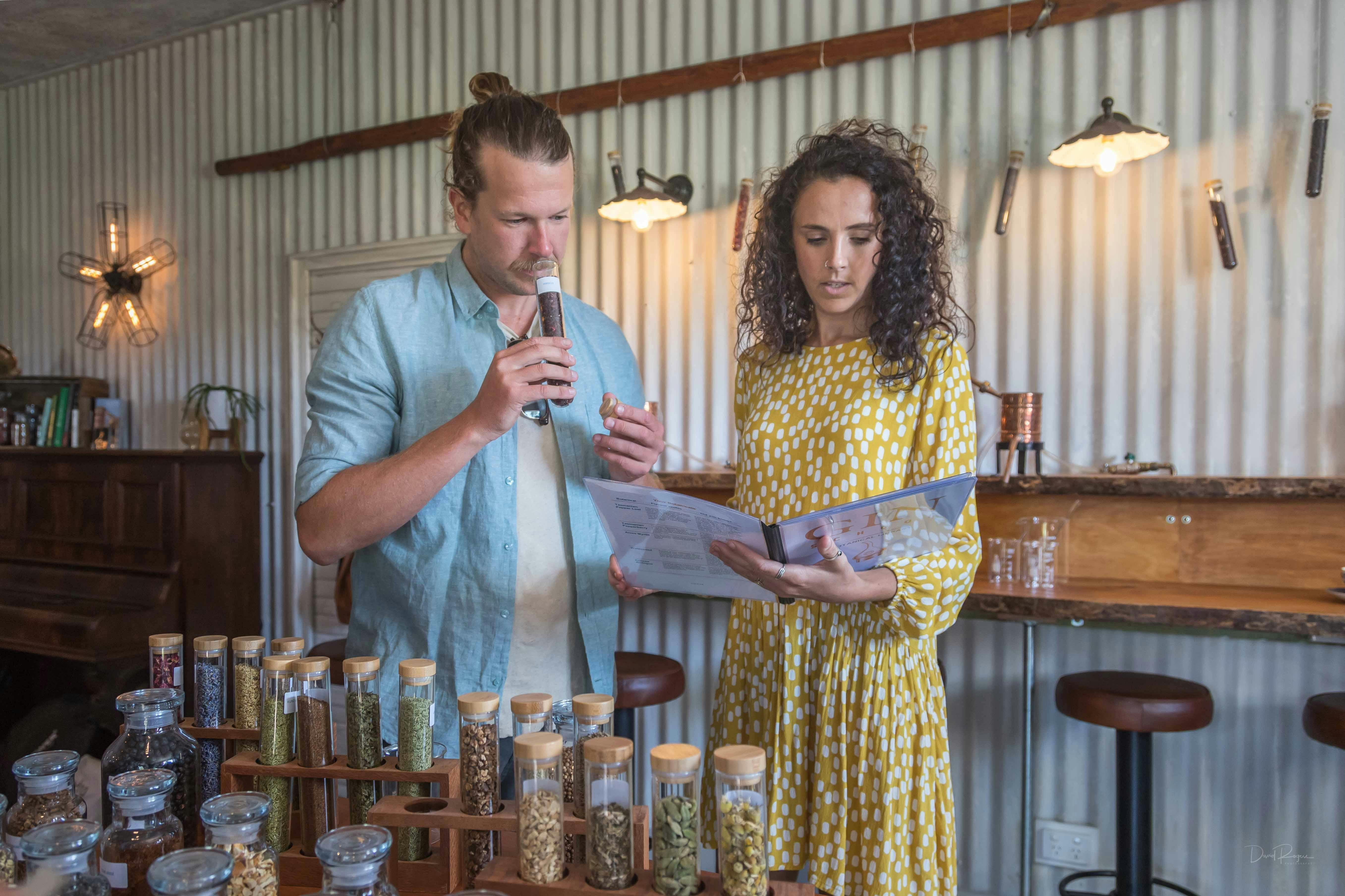 Man sniffing contents of test tube of hibiscus. Woman standing nest to him reading from booklet.