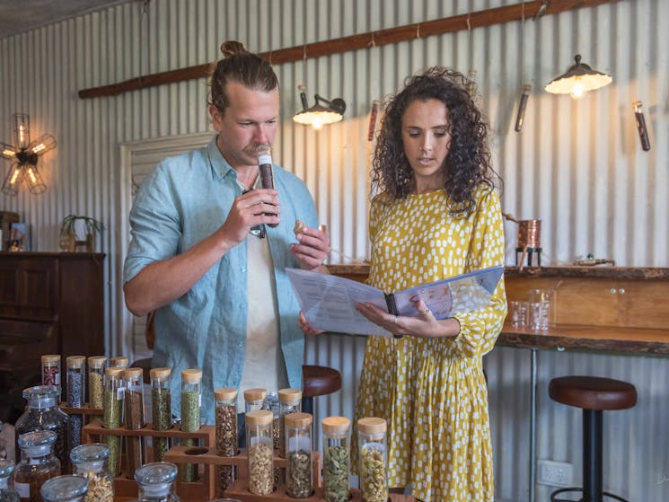 Man sniffing contents of test tube of hibiscus. Woman standing nest to him reading from booklet.