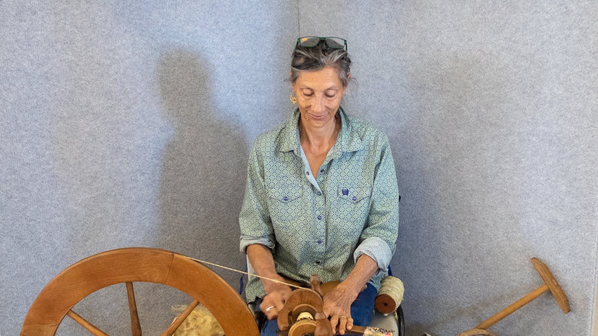 Woman sitting at wool spinning wheel Woman sitting at wool spinning wheel