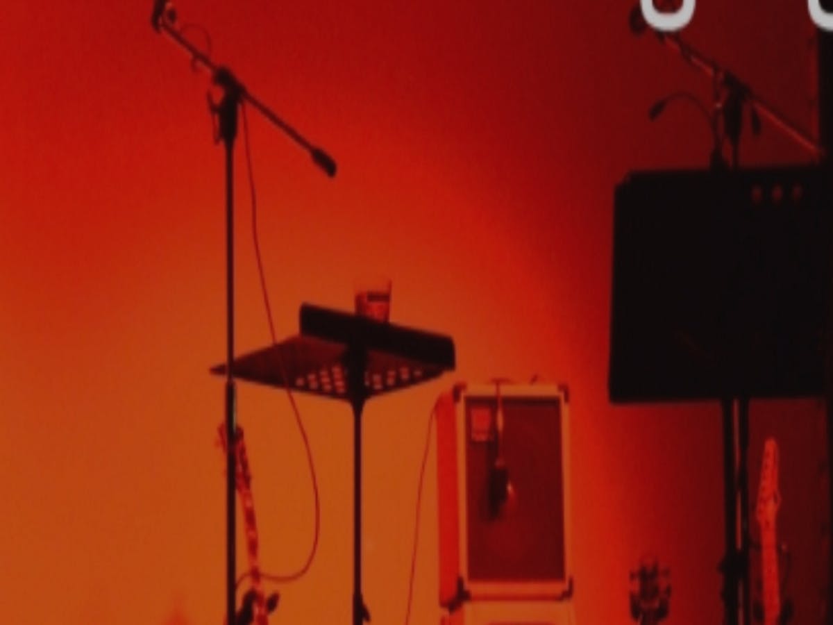 Music stand and mic stand against an orange background