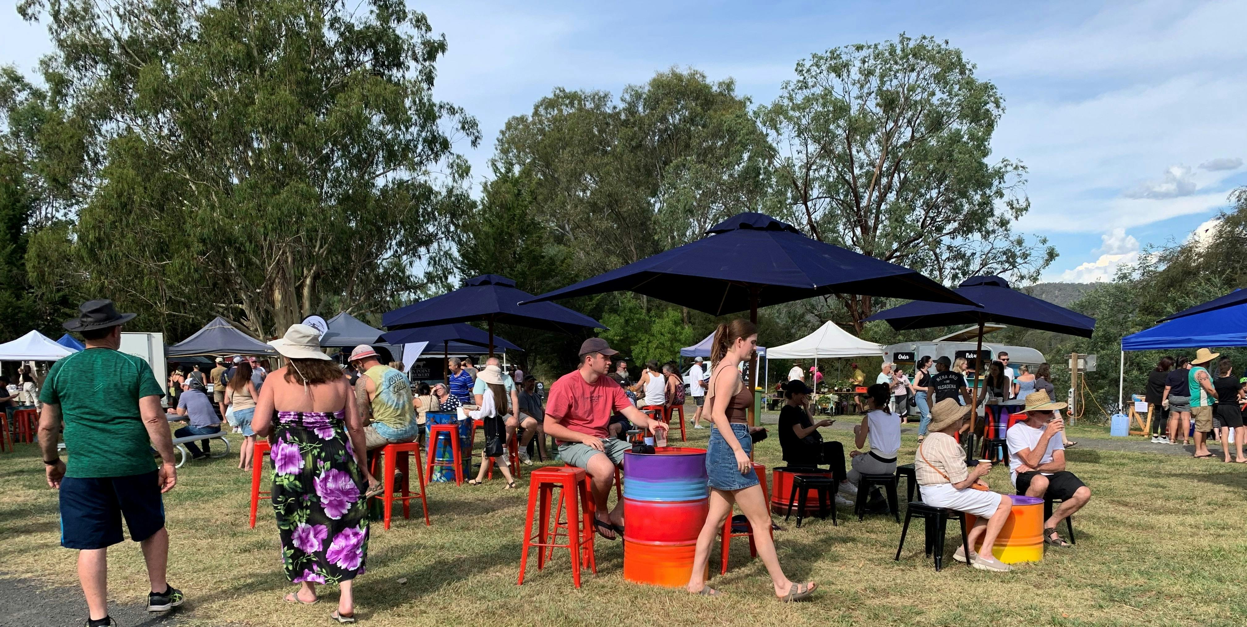 people sitting on stools with umbrellas in an open ground