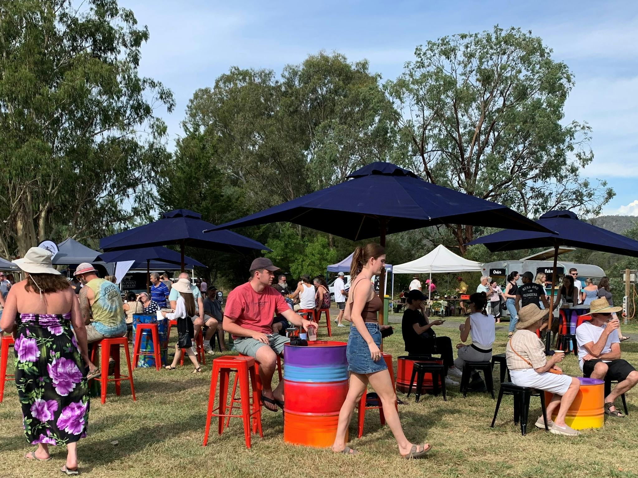 people sitting on stools with umbrellas in an open ground