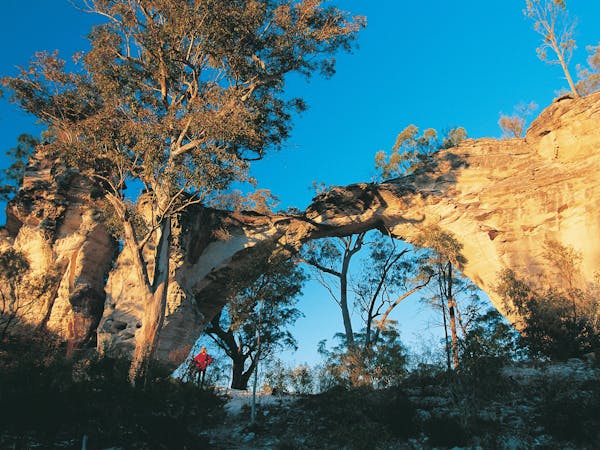 Person standing under Marlong Arch rock formation.