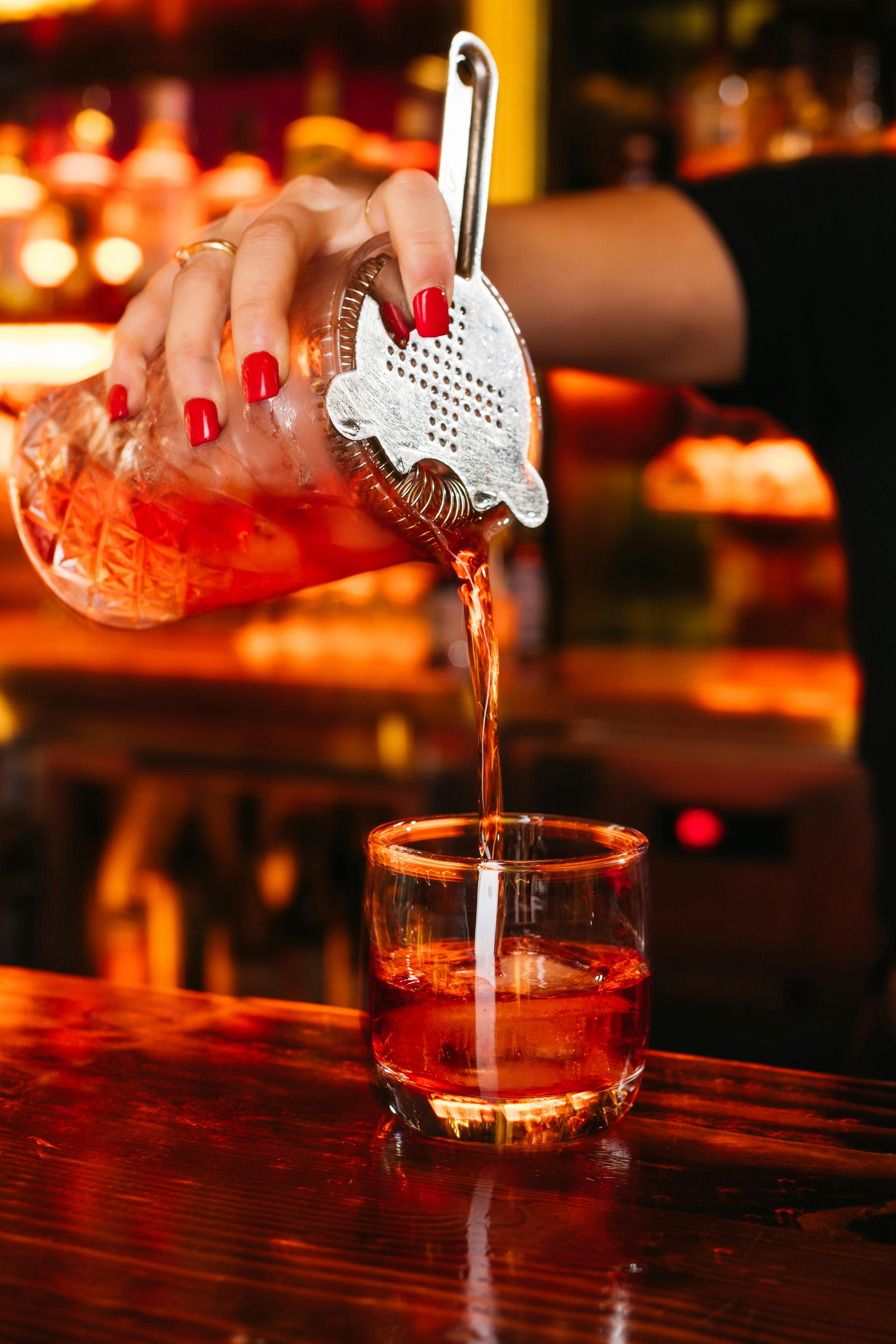 A negroni is being poured out of a cocktail shaker.