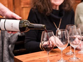 Red wine being poured into glass in front of customer.