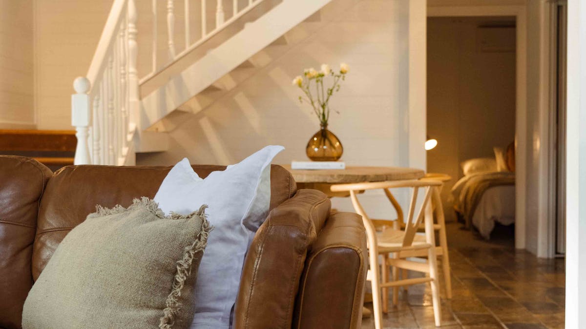 Main house living space and dining space with leather couch and timber dining table Main house living space and dining space with leather couch and timber dining table