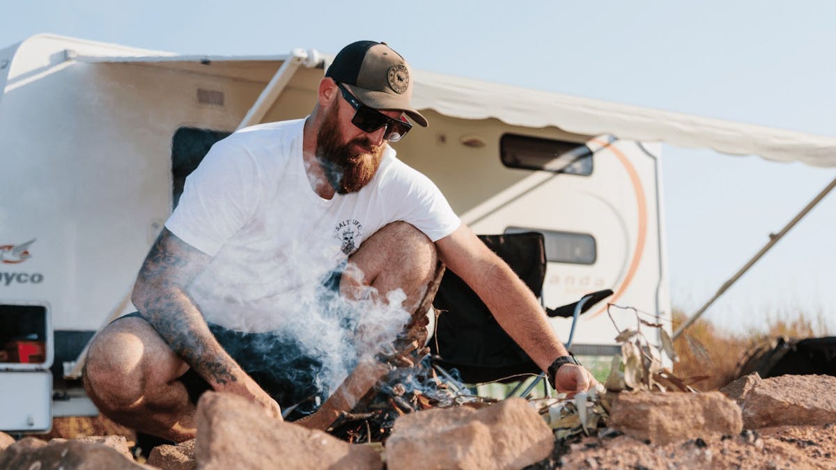 Man making fire in a fire pit while camping