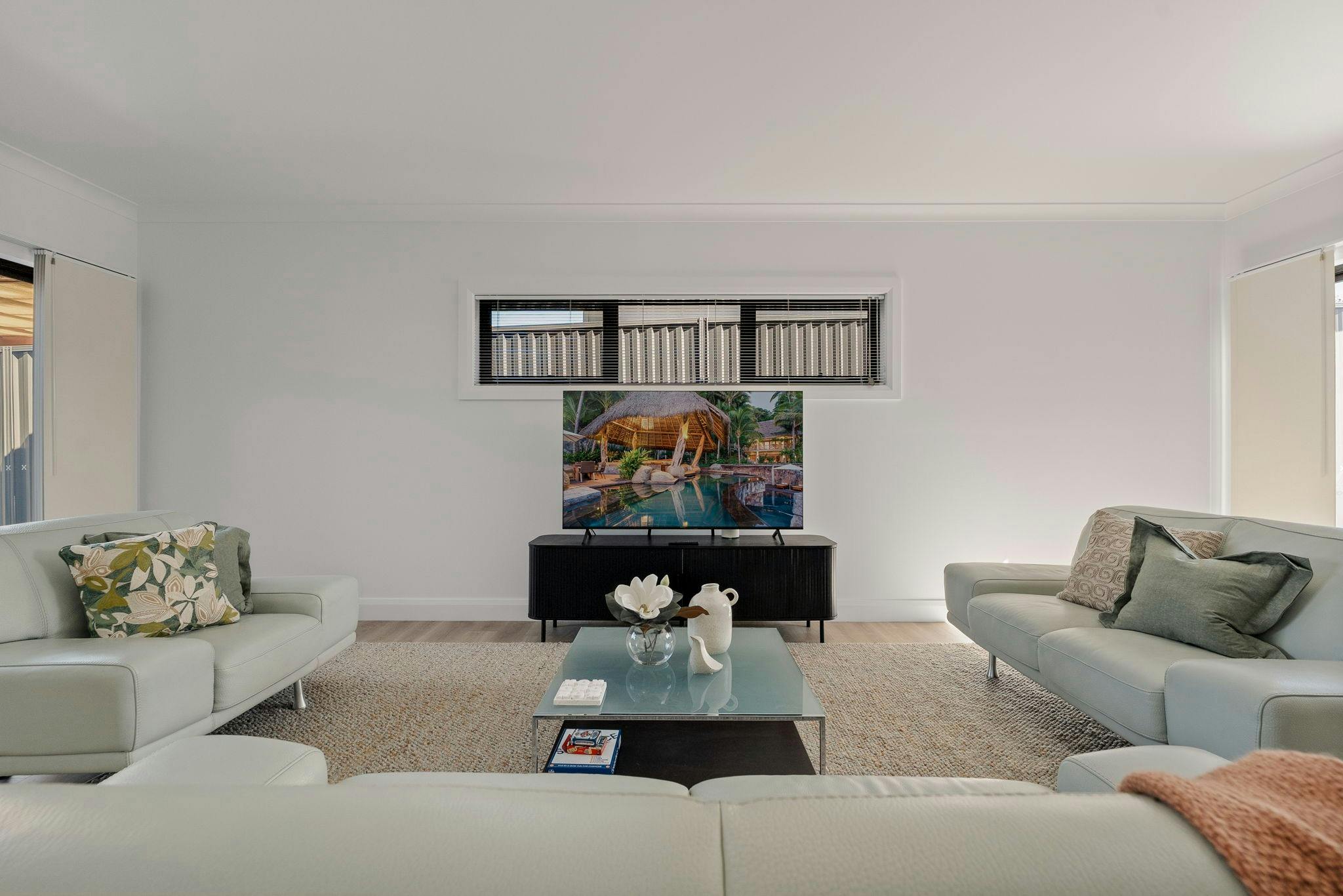 3 large couches, tv, tv entertainment unit and coffee table. Large rug with lots of windows.