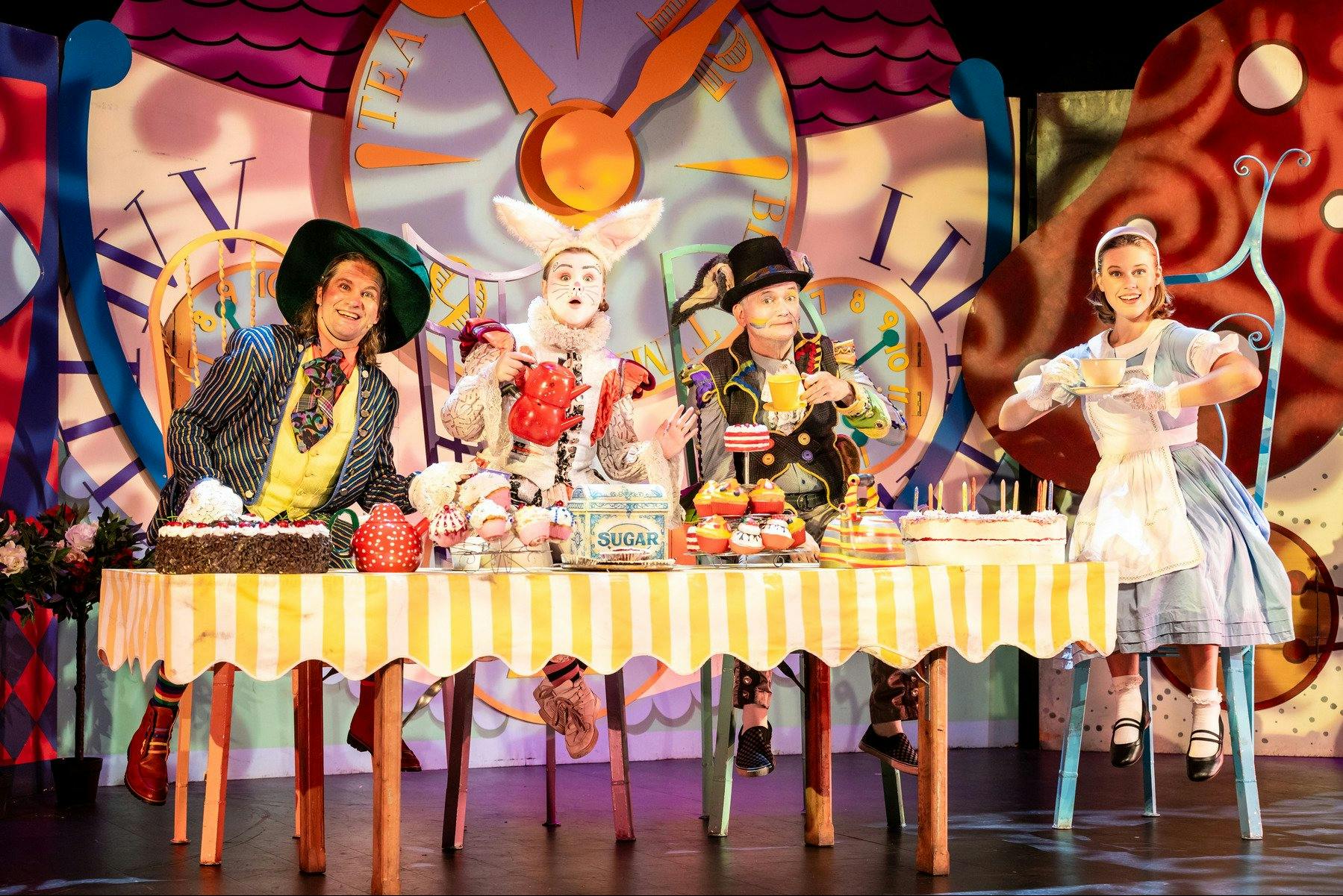 Four Alice in Wonderland characters have a whimsical tea party against a fantastical backdrop.