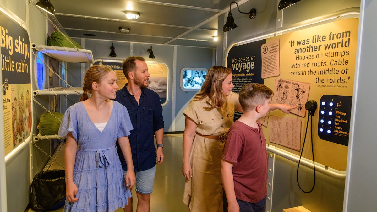 a family walking through an exhibit of the Queen Mary inside the Secret Base