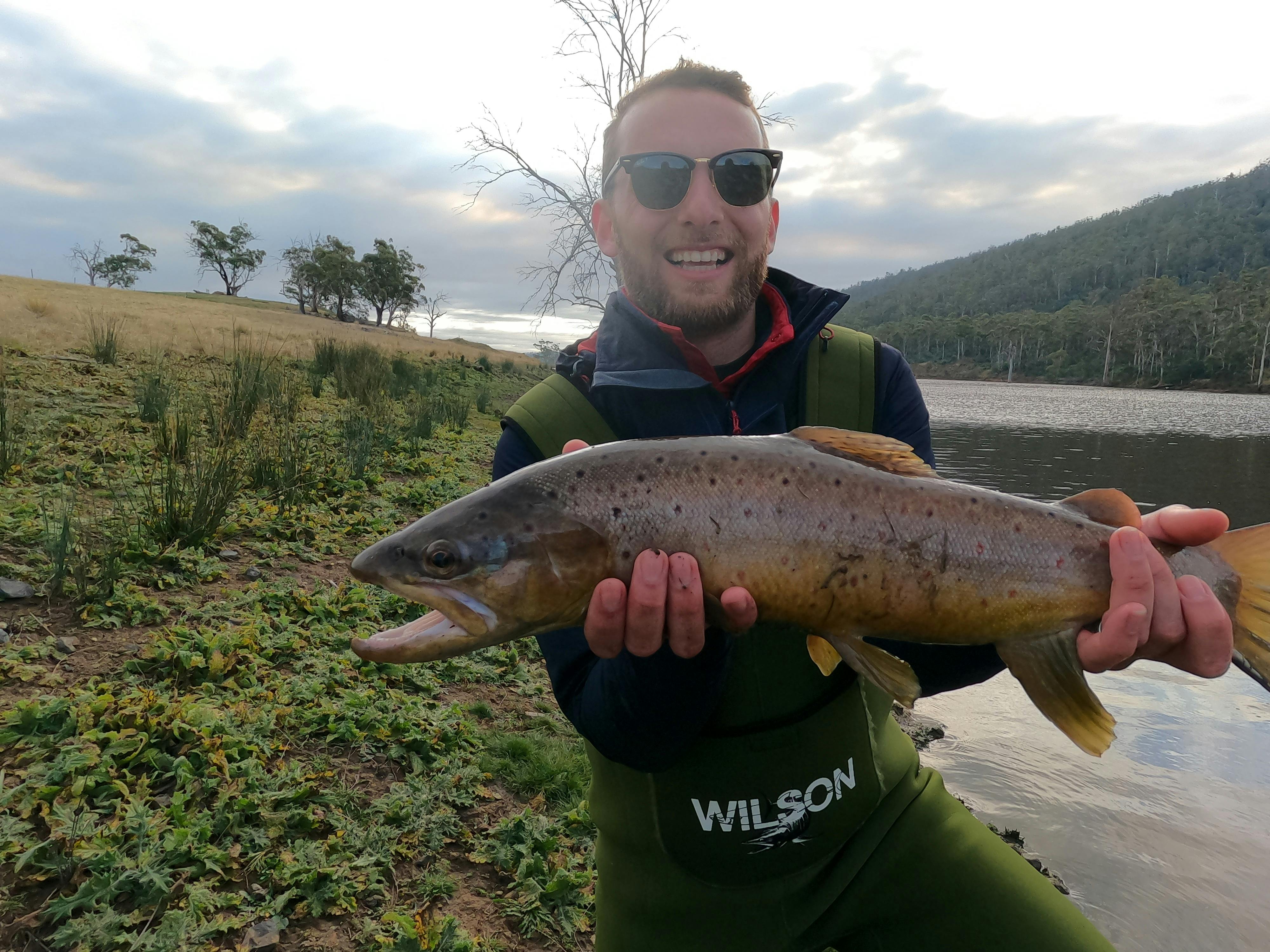 A fisherman holding a large brown trout  he just caught at 28 Gates
