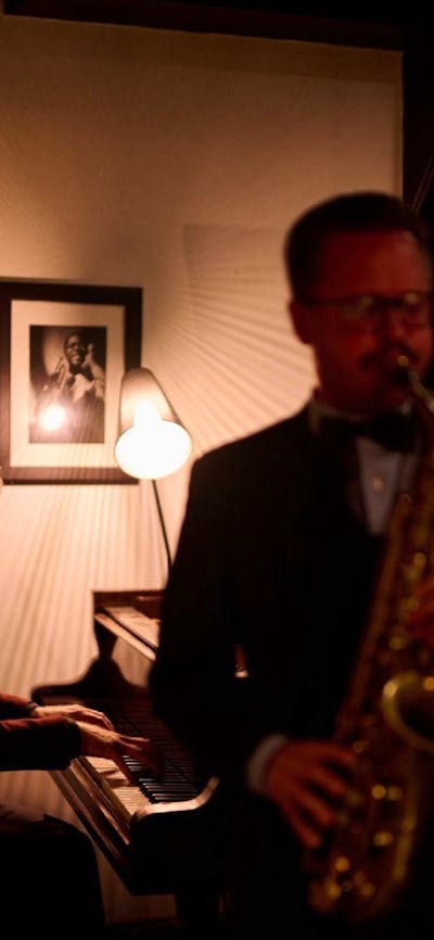 Musicians playing piano and saxaphone in a dimly lit bar