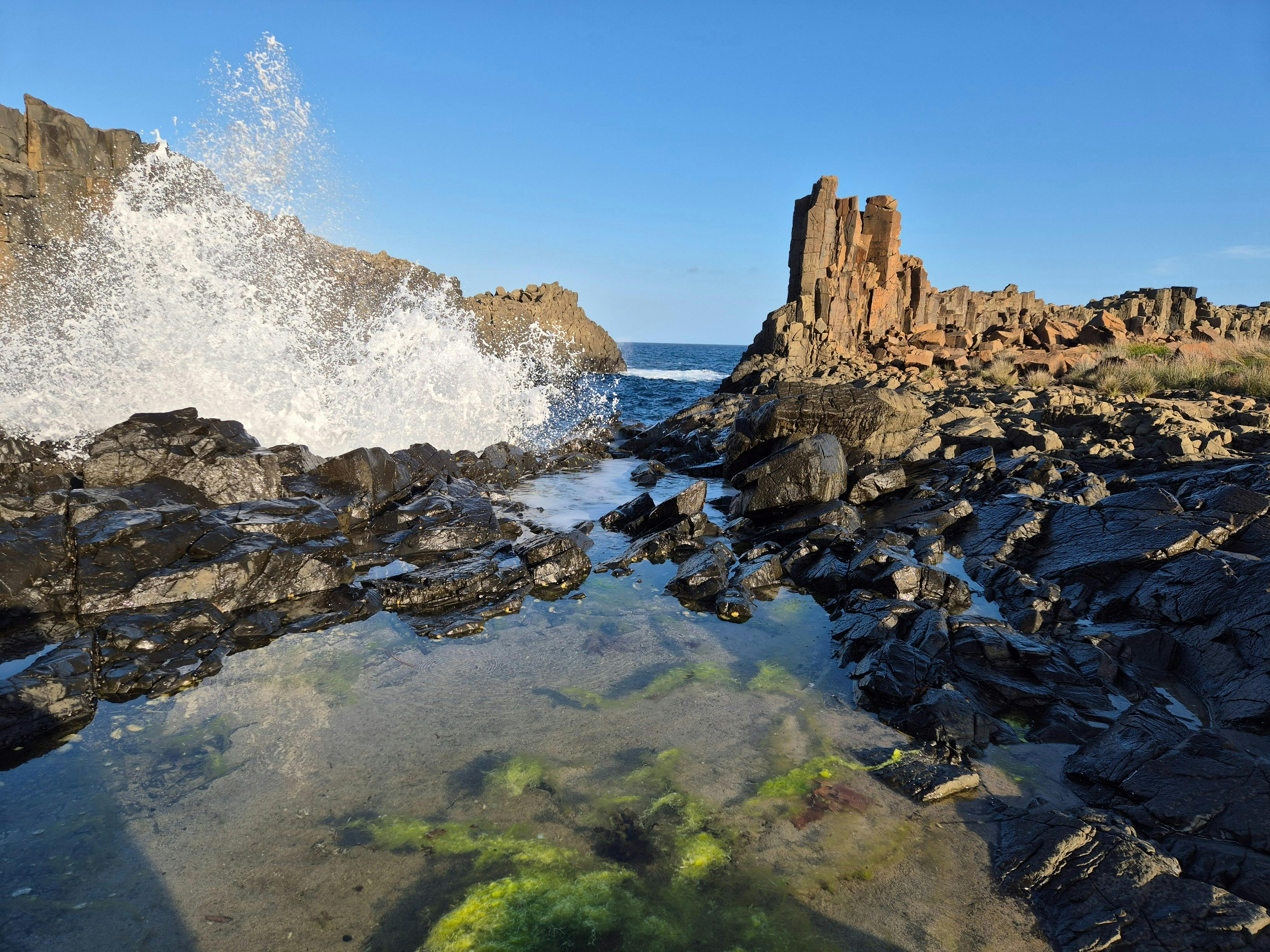 Waves crash on rugged basalt rocks