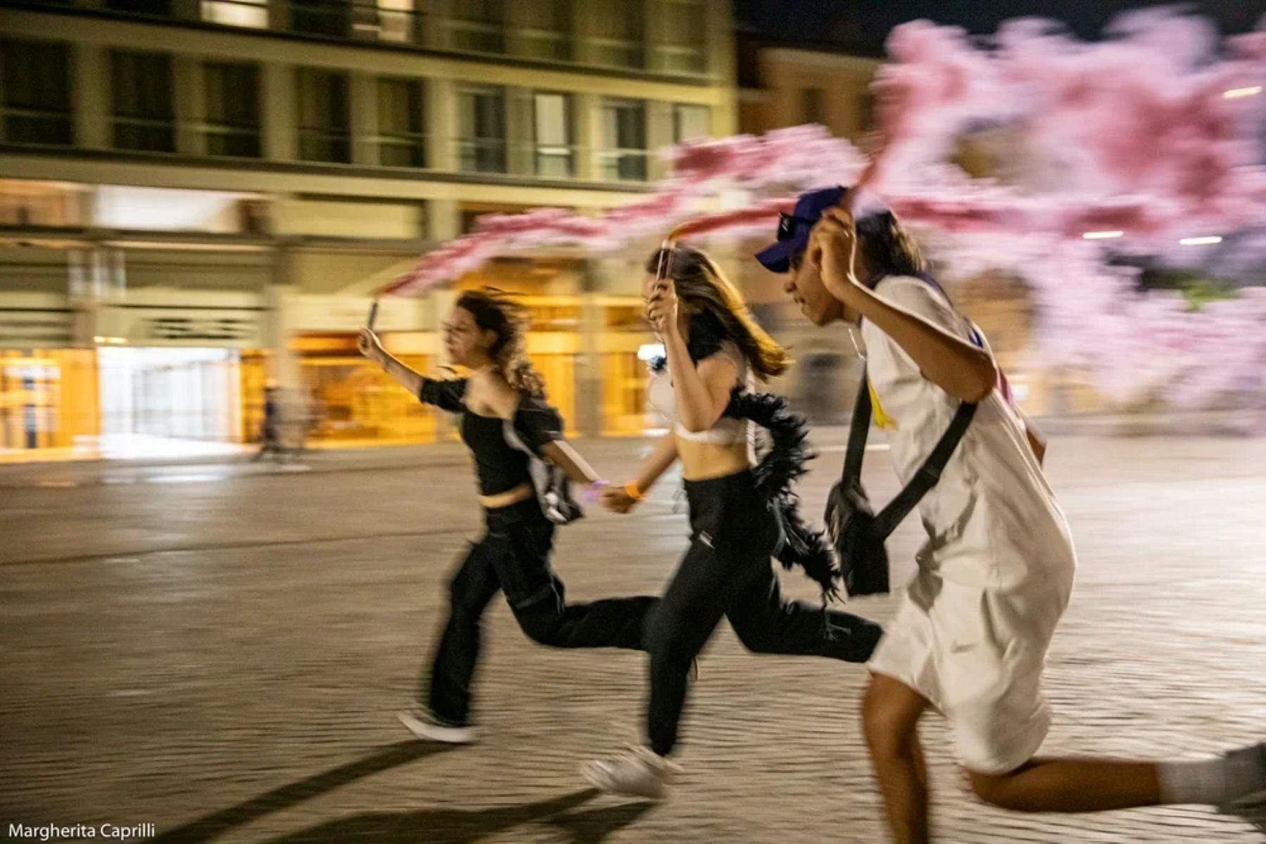 three teenagers running at night with pink flares