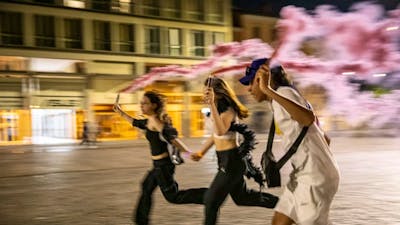 three teenagers running at night with pink flares