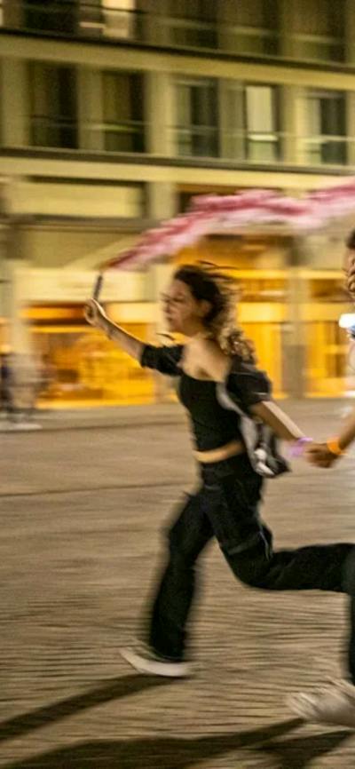 three teenagers running at night with pink flares