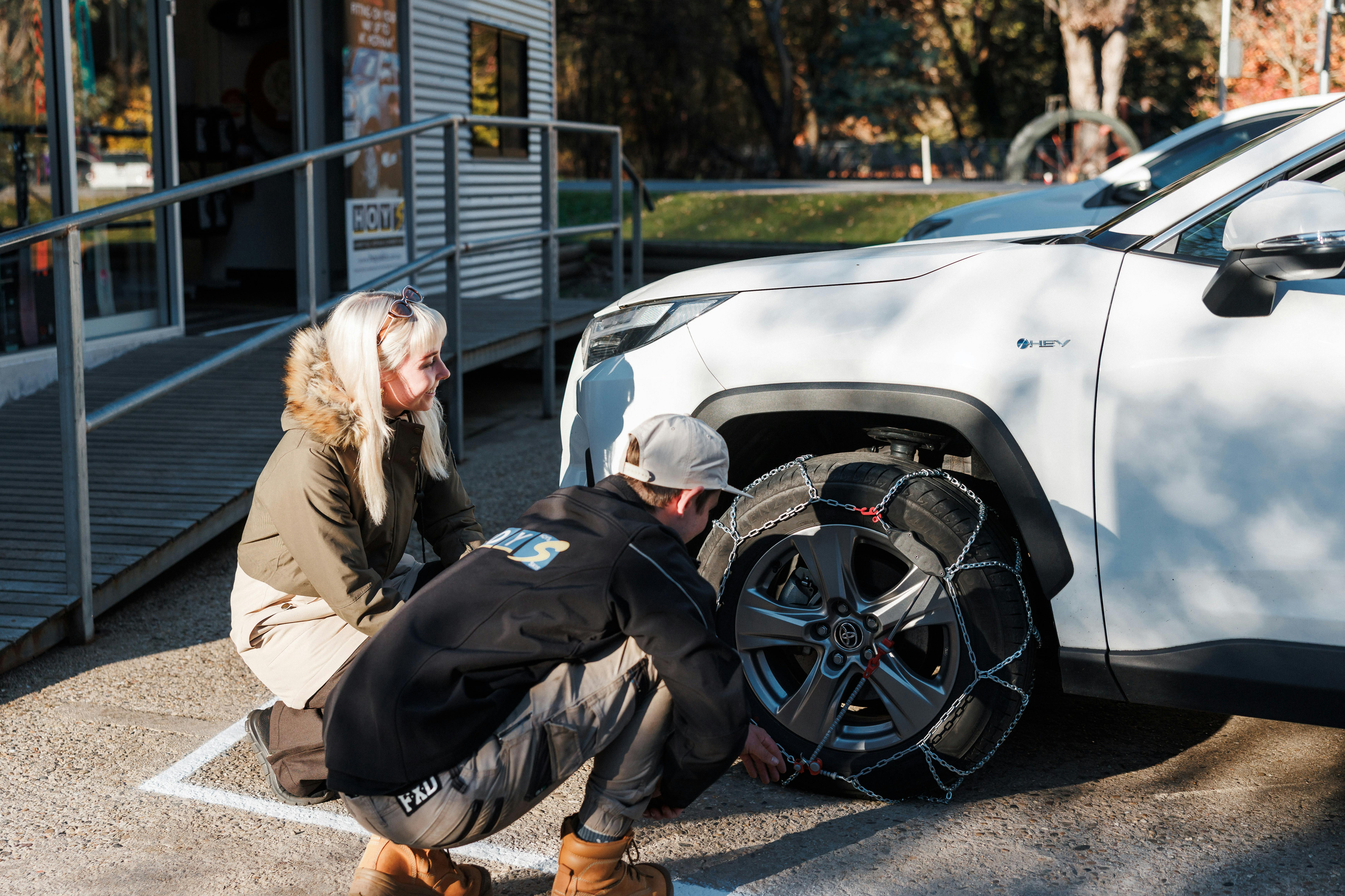 Hoys staff showing a guest how to fit chains to her car