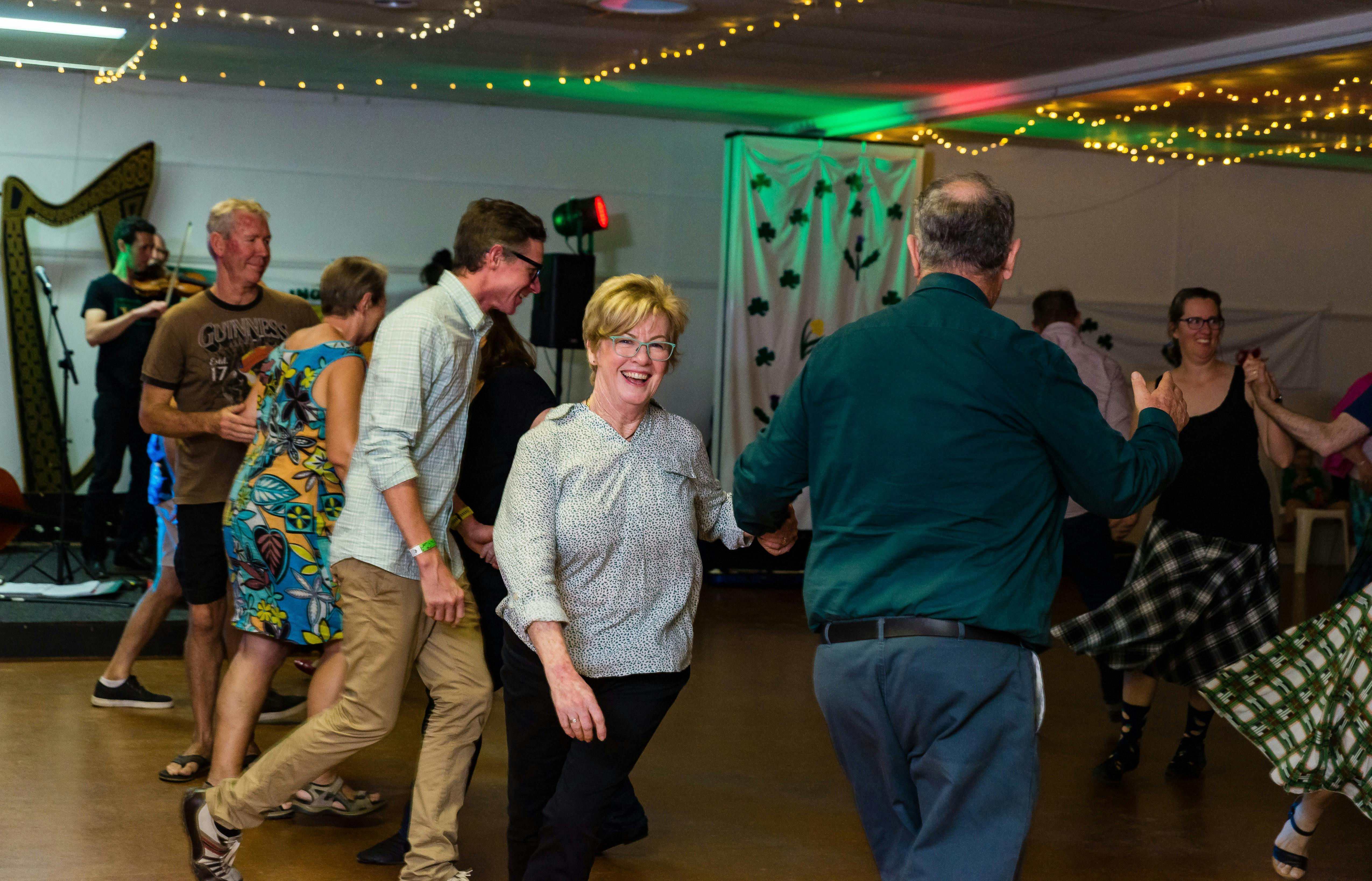 A ceilidh (traditional Irish or Scottish dance) dancer smiles as she is twirled by her partner