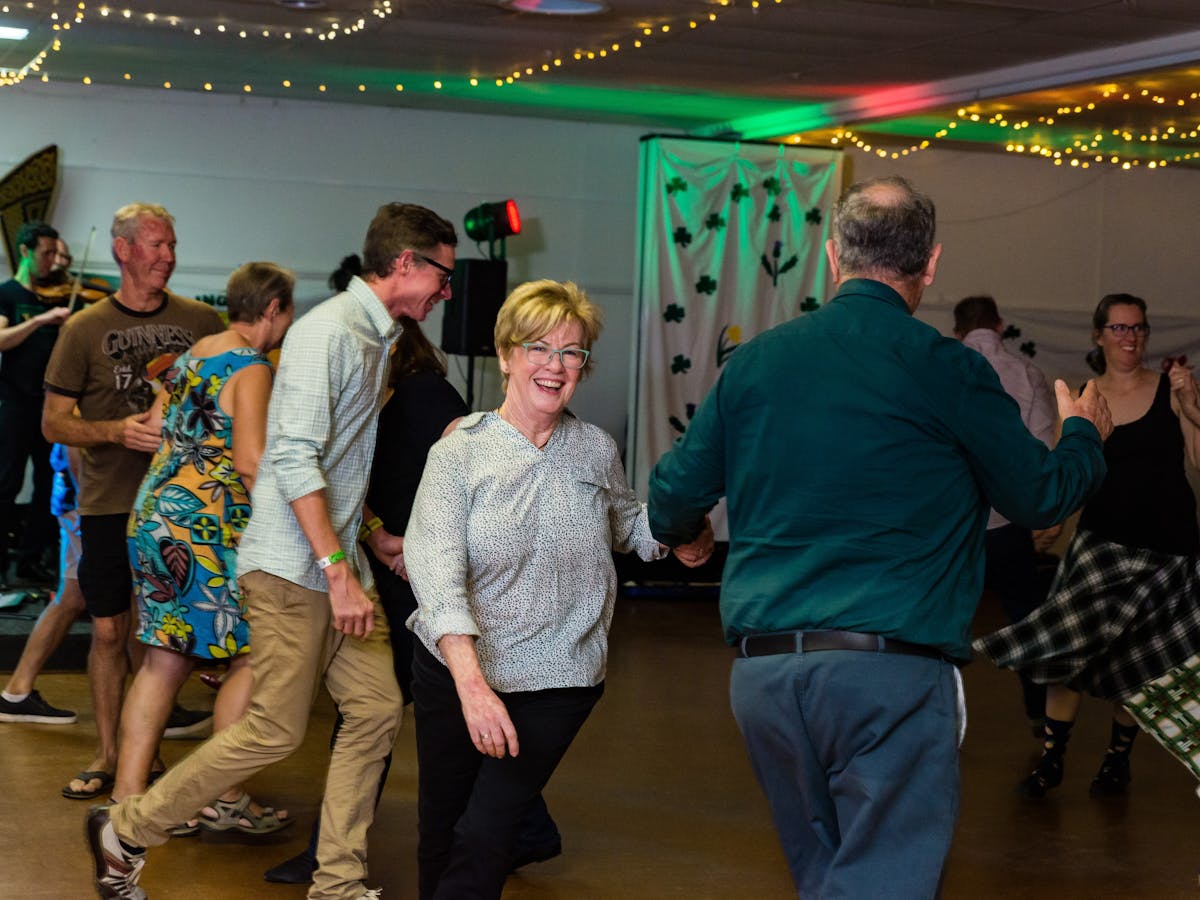 A ceilidh (traditional Irish or Scottish dance) dancer smiles as she is twirled by her partner