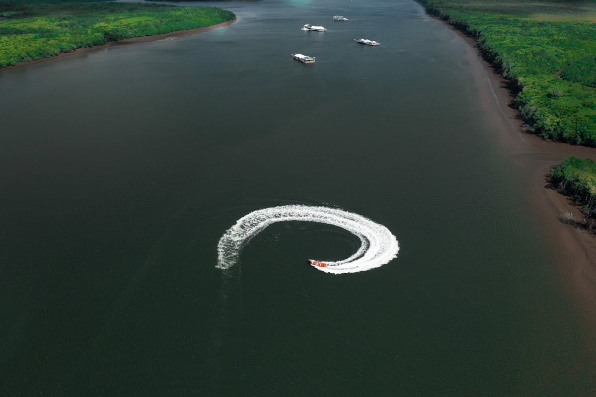 Drone shot of the Cairns Jet Boat Bad Fishy creating waves while spinning in Cairns