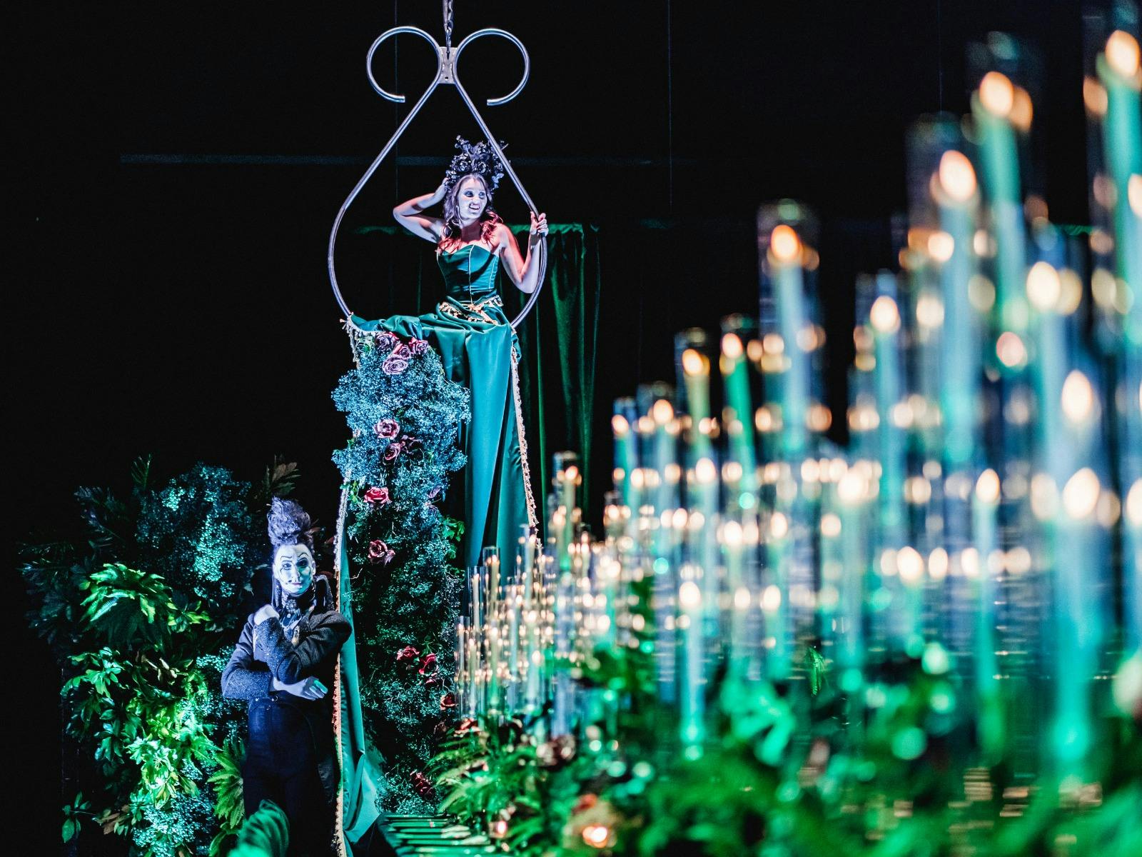 A lavish green banquet table with aerialist and candles
