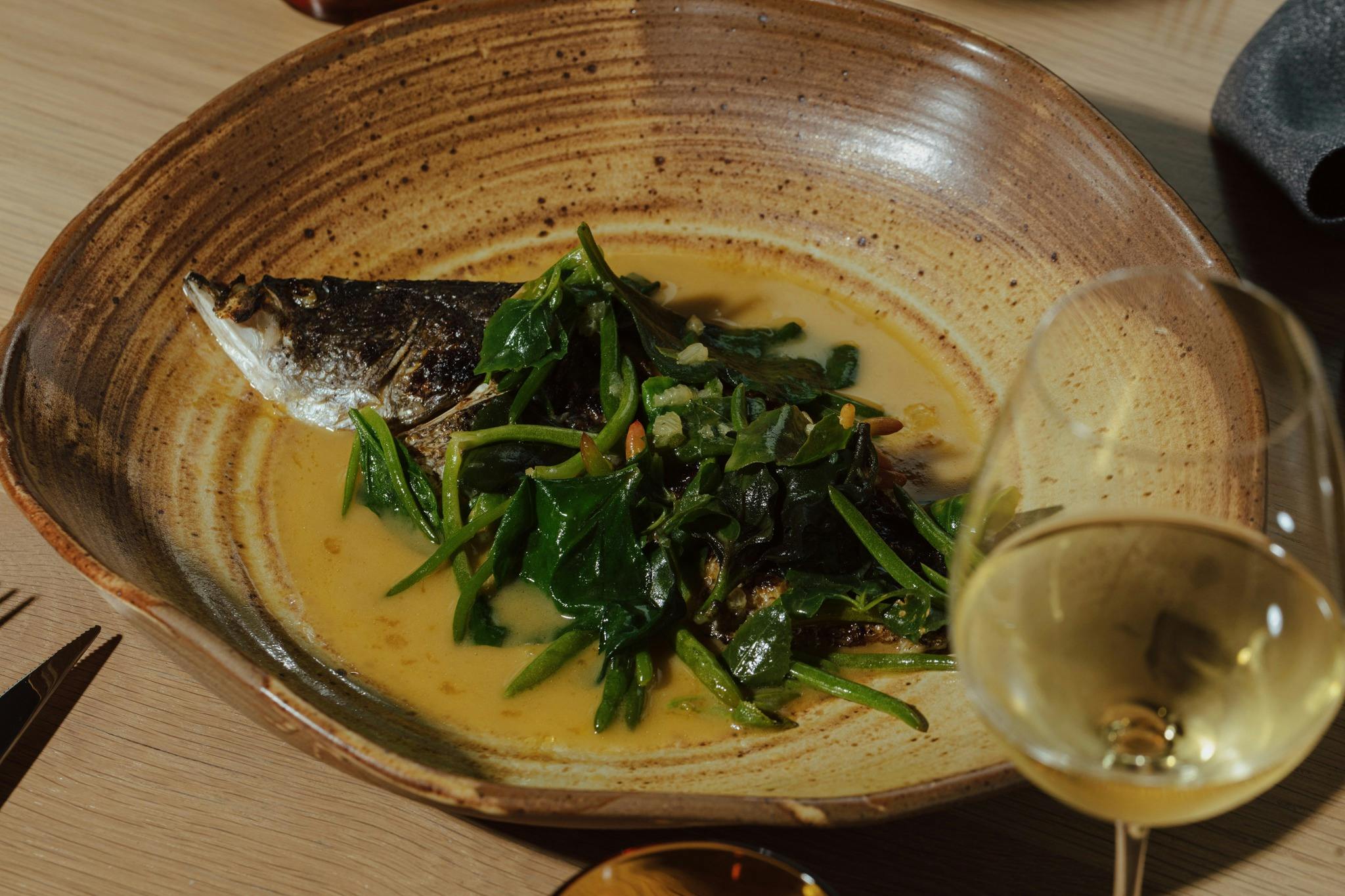 Barramundi cooked over coals, citrus and coastal greens