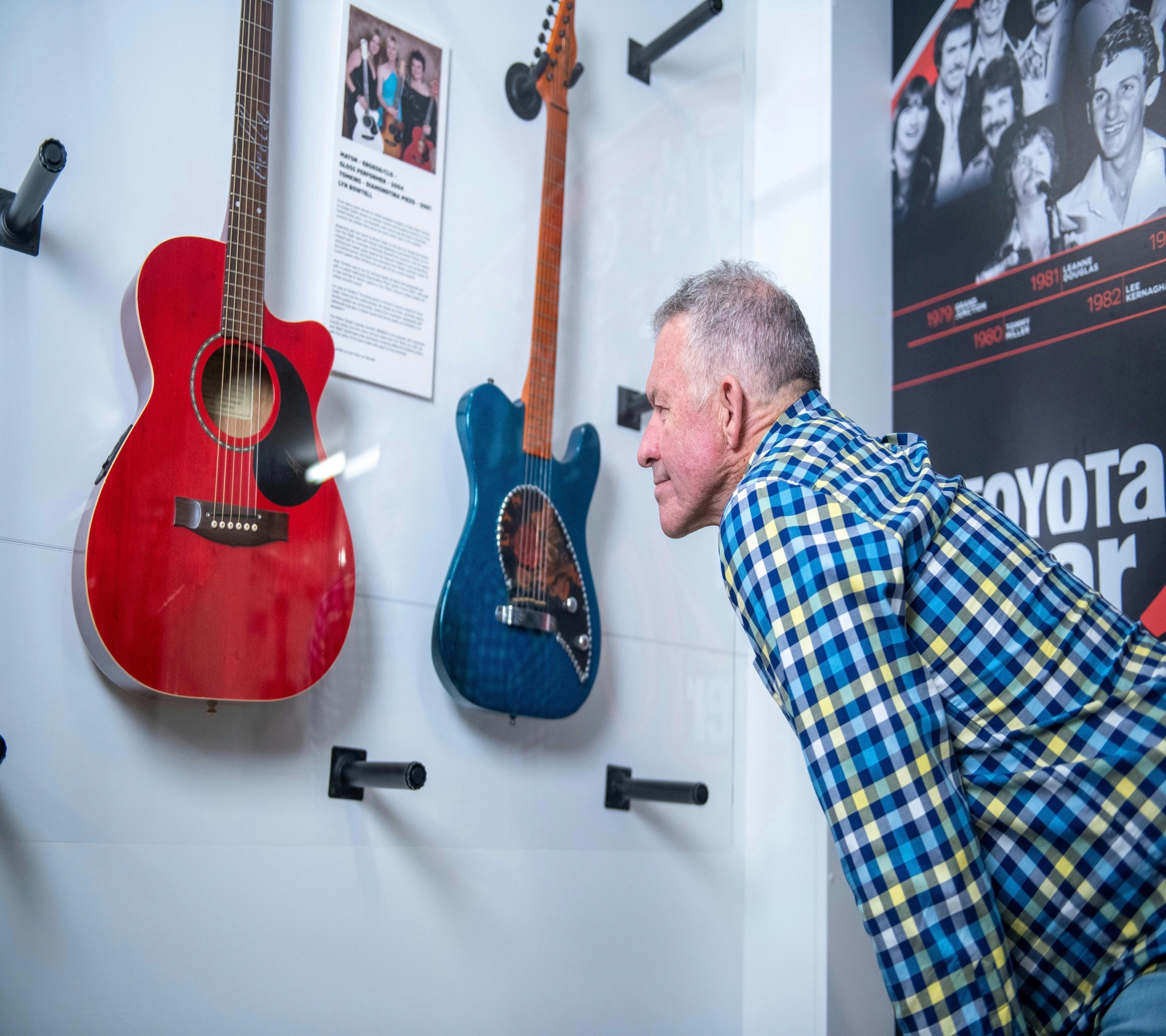 Elderly gentleman looking at a red guitar