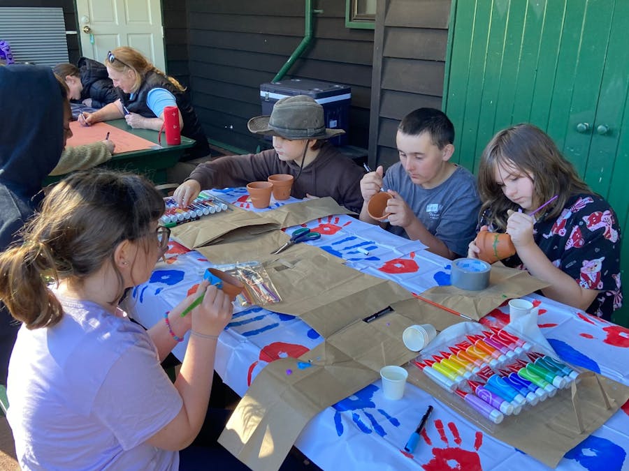 Kids gathered around a table enjoying a pot painting arts and craft activity