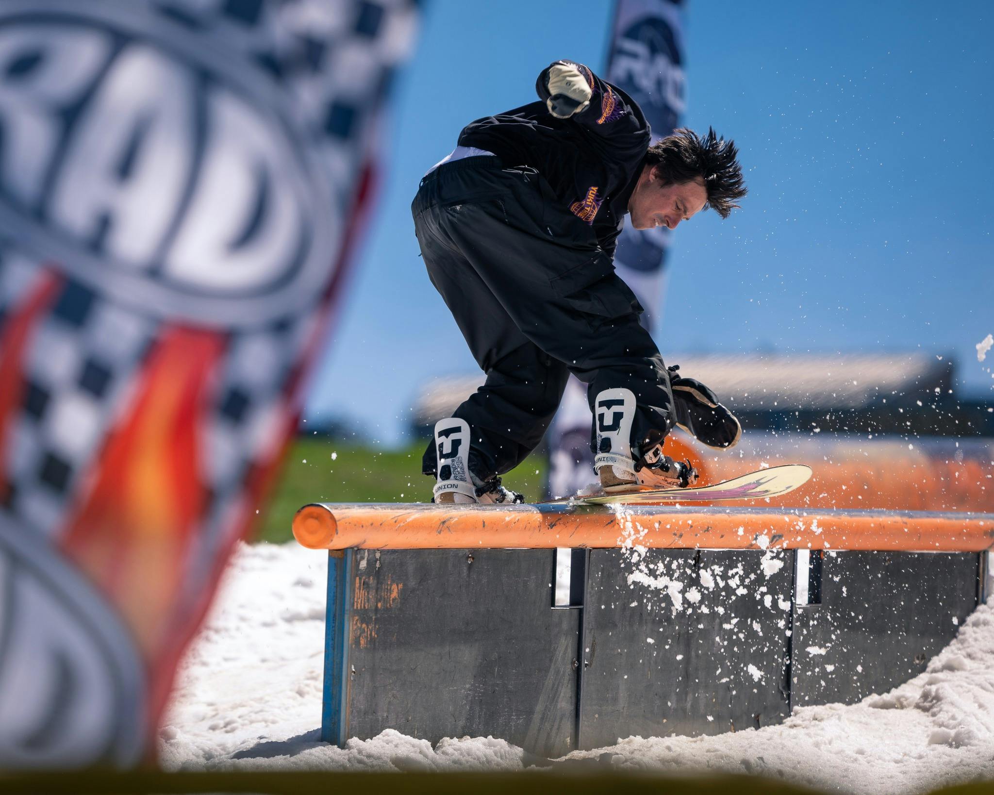 Snowboarder sliding across rail