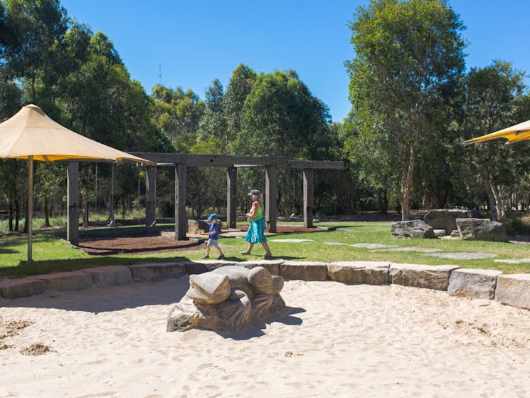 Large sandstone lizard sculpture in sandpit and playground