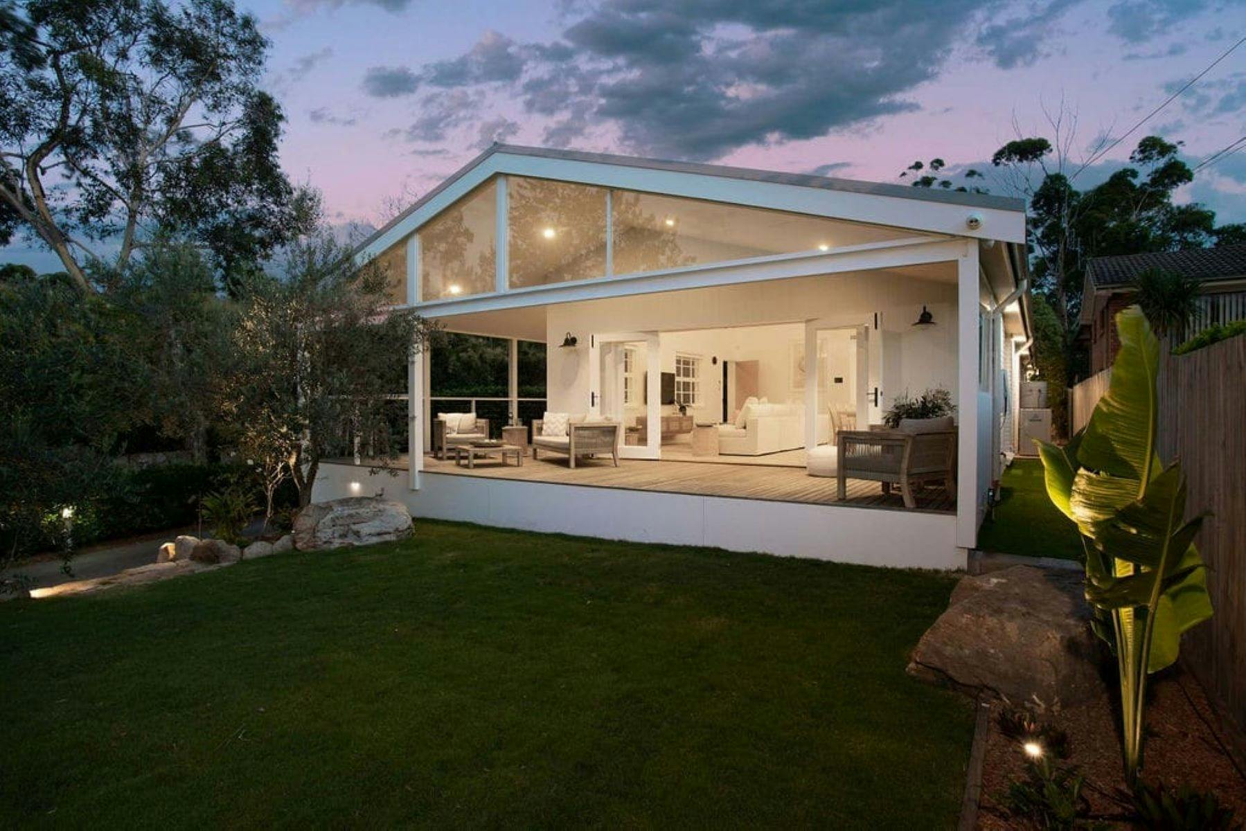 Image of the back deck of property. You can see purple skies as it is dusk. Lights are dim