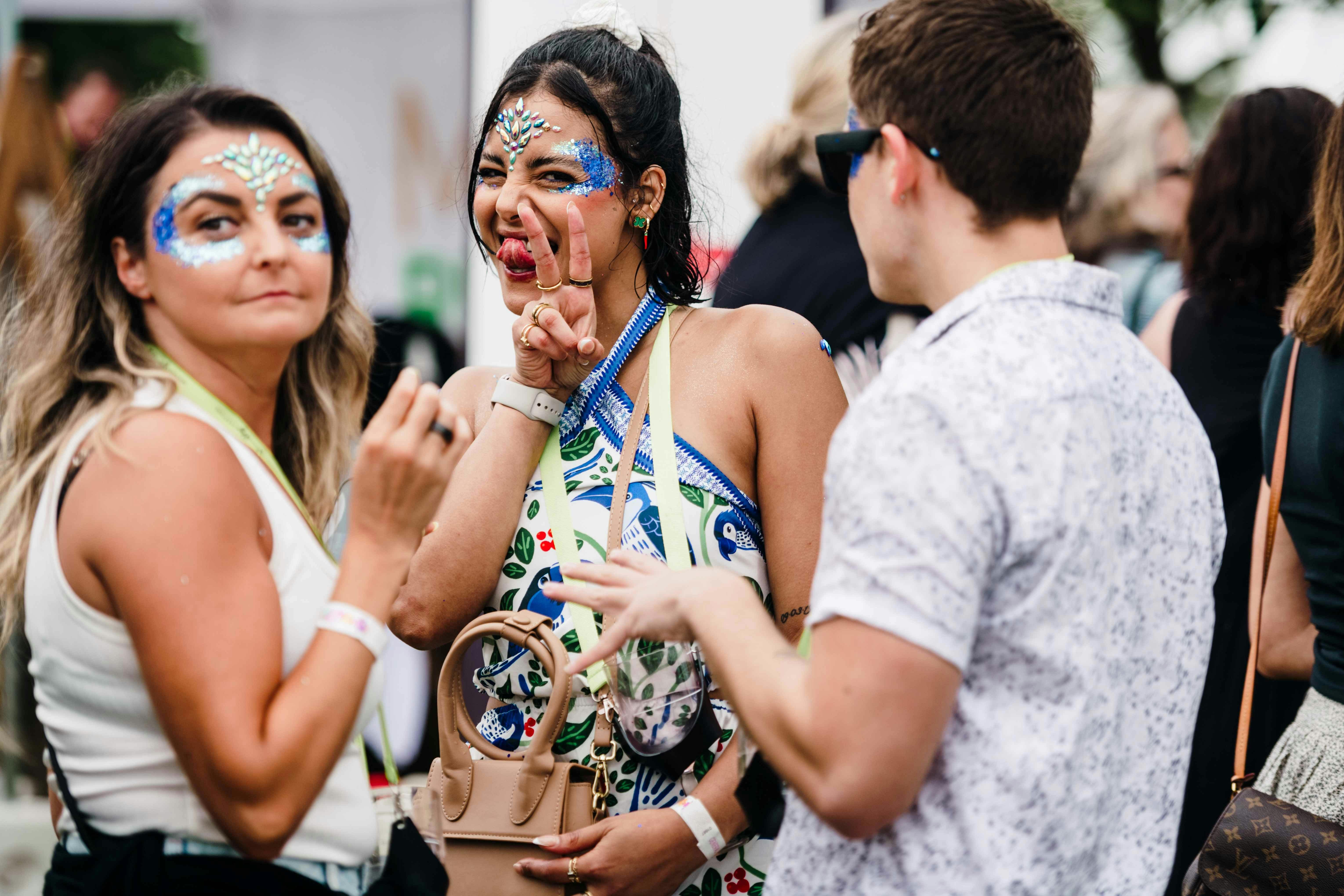 Cheeky candid photo of a woman with glitter on her faceb giving the peace sign