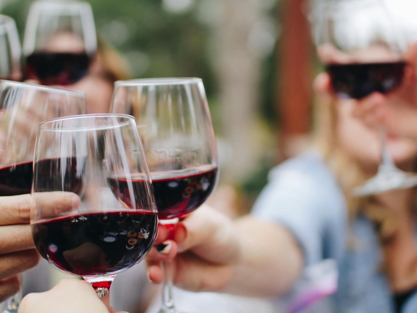 Five hands holding and making cheers with five glasses of wine