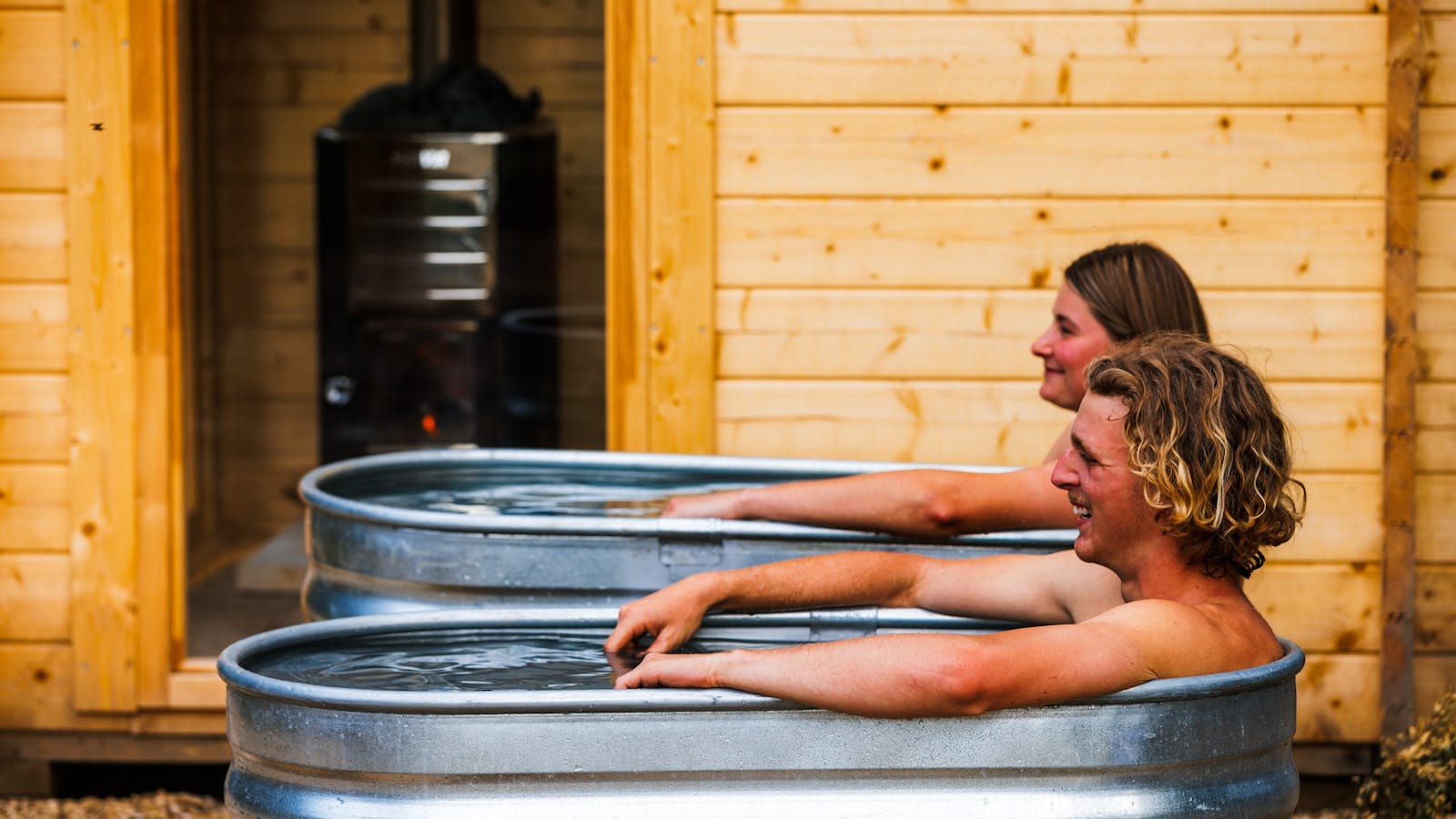 A couple enjoying a cold plunge with a traditional wood fired sauna at maydena bike park