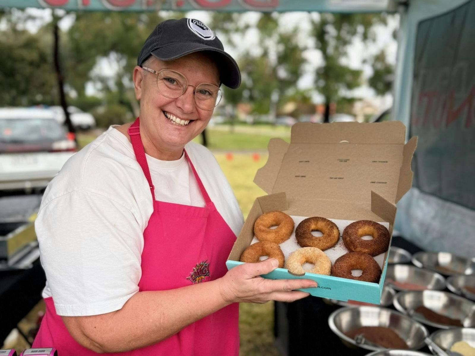 A woman showing donuts she is selling
