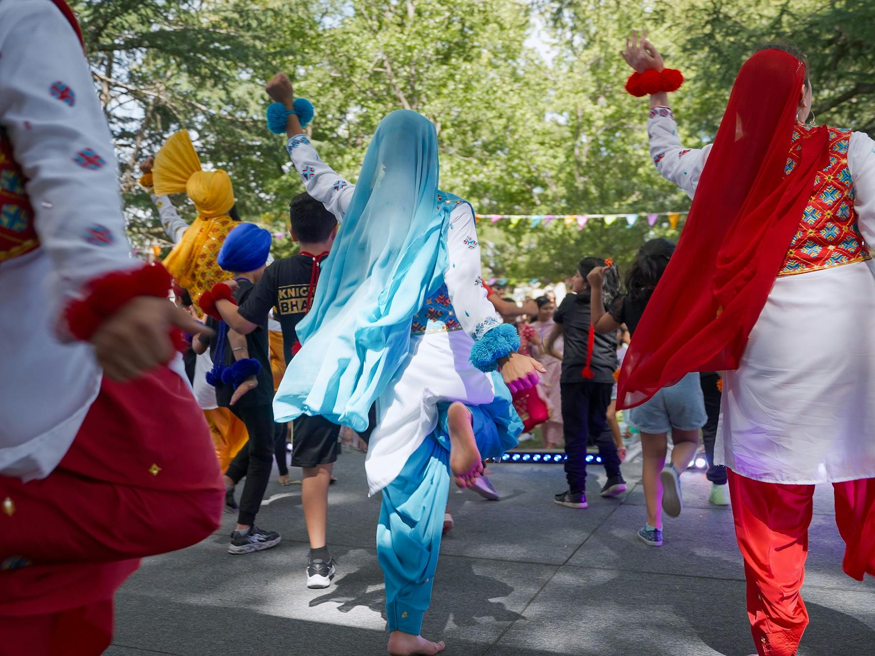 Photo from behind of sevreal dancers on stage in colourful costume