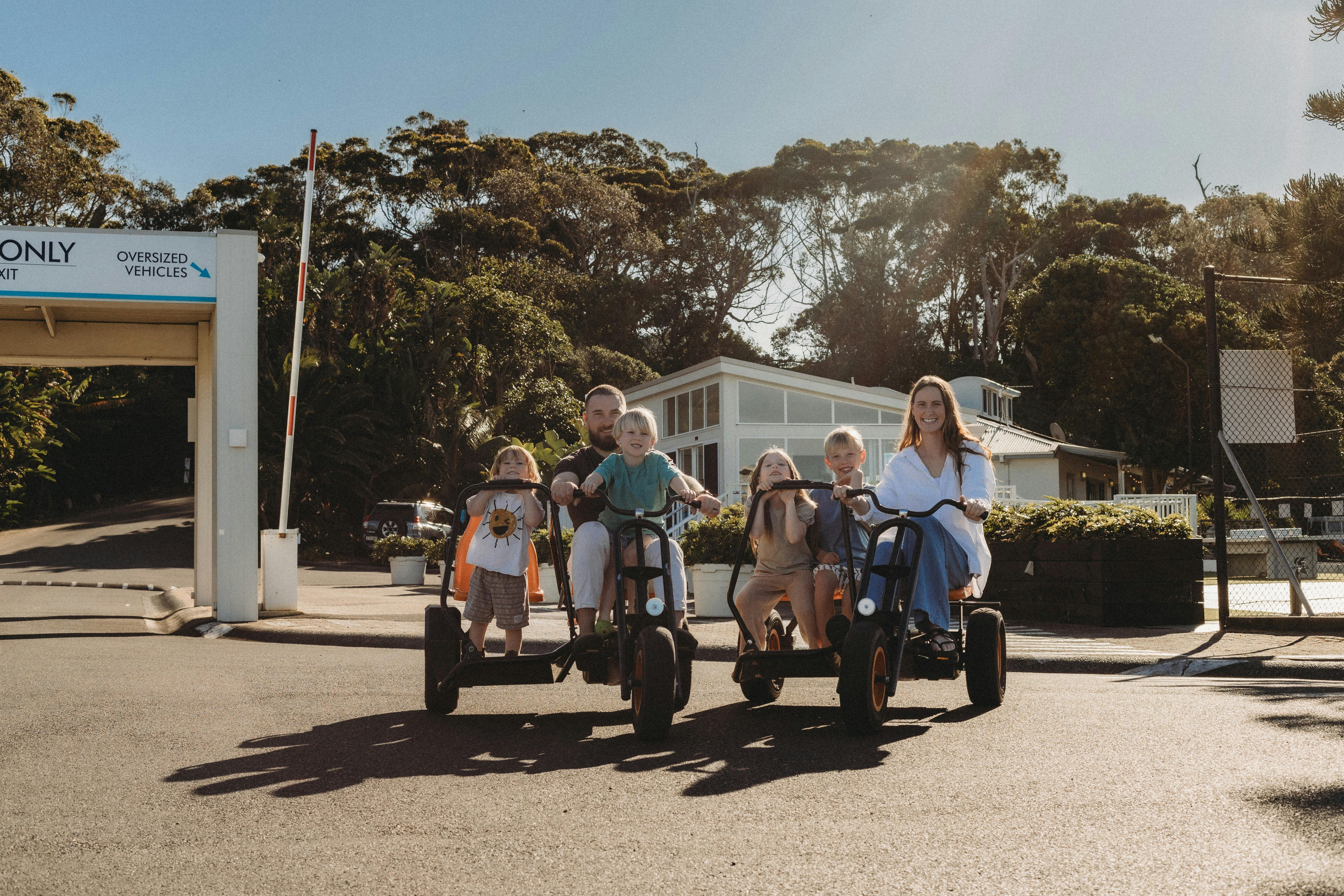 在蓝湖海滩度假村中央海岸家庭假日公园住宿期间，一家人骑着脚踏车。