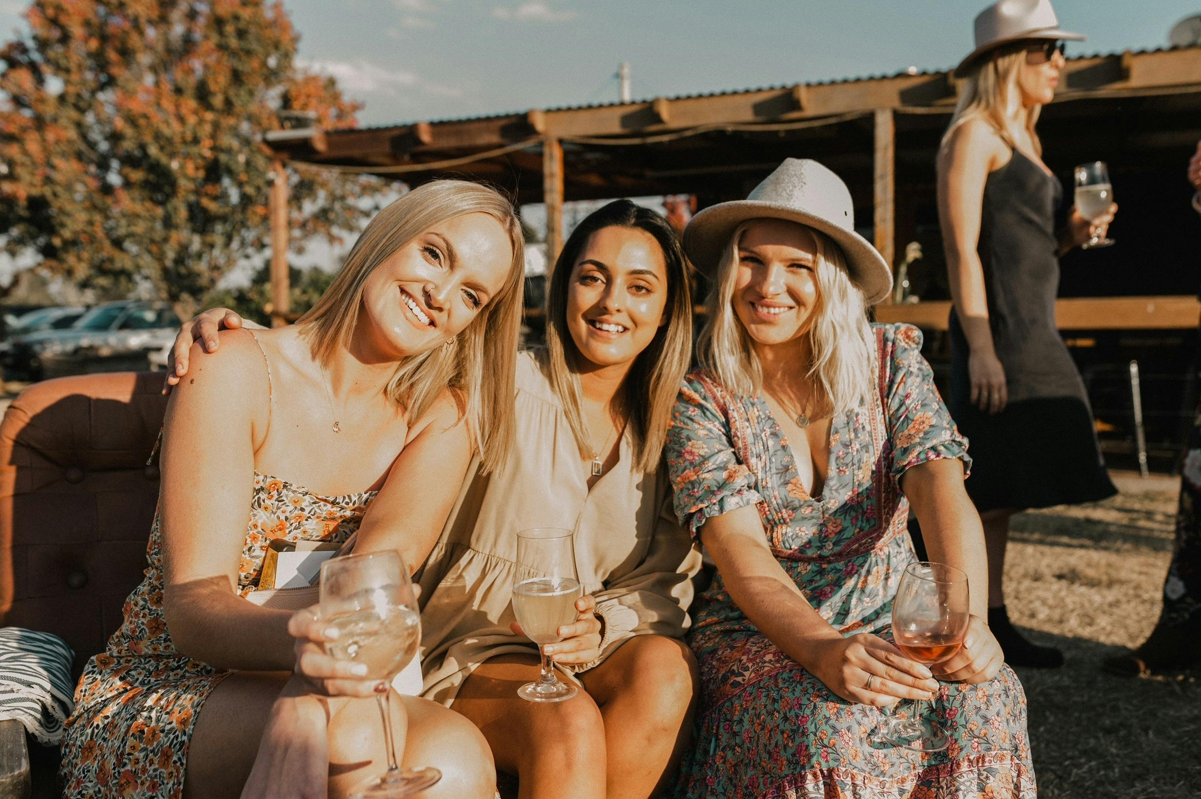 ドレスと帽子を着て秋の太陽の下でワインを飲む3人の女性