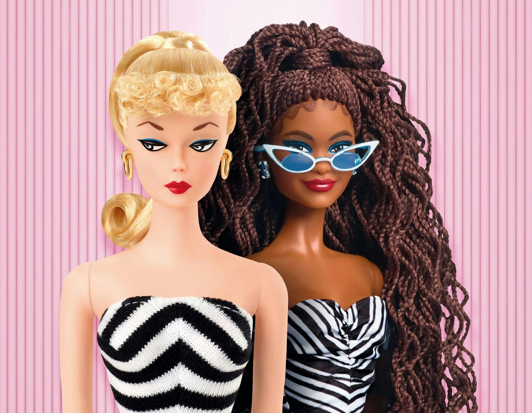 2 barbies standing in front of a pink background