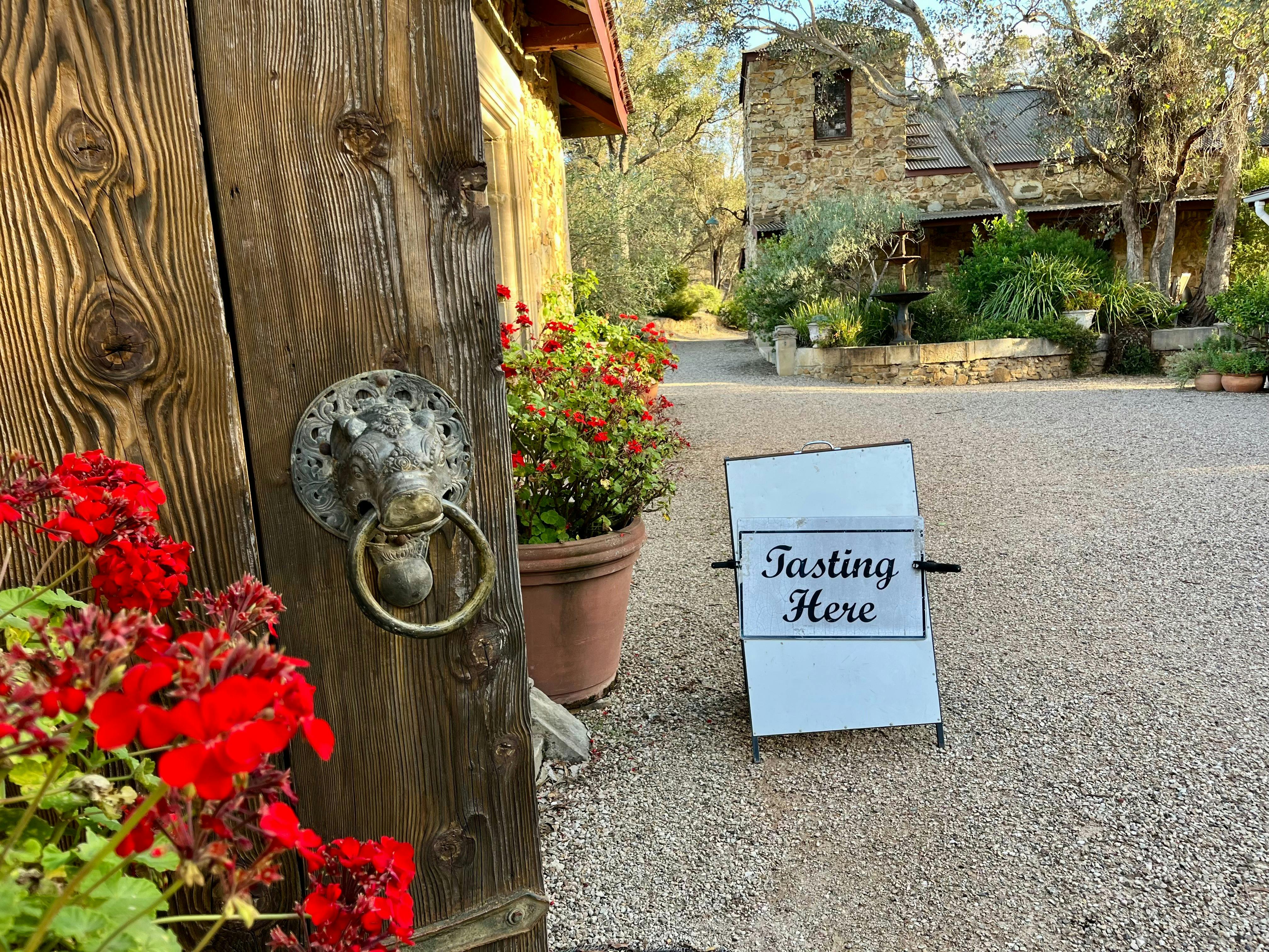 A sign reading tasting here adjacent to a open timber door