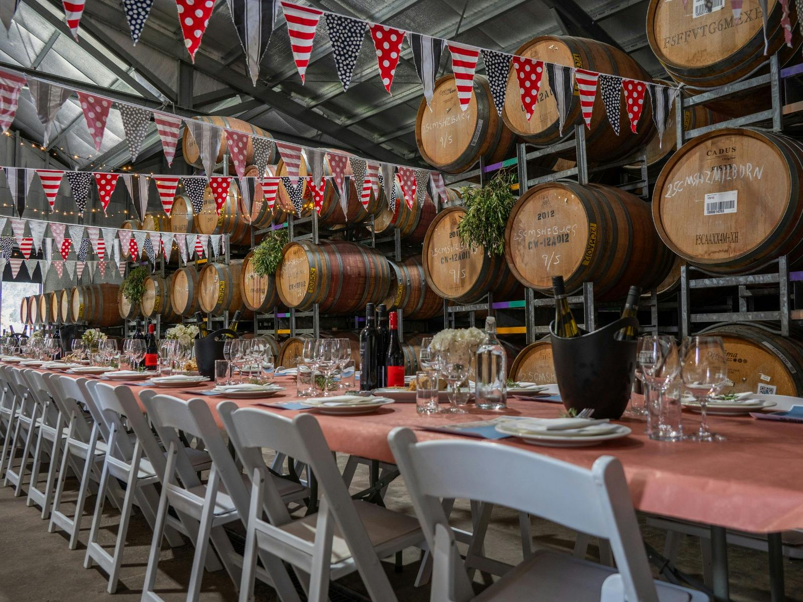 long tables and white chairs set under red and white flags among barrels