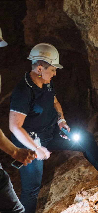 Two people using a torch to look at a large rock