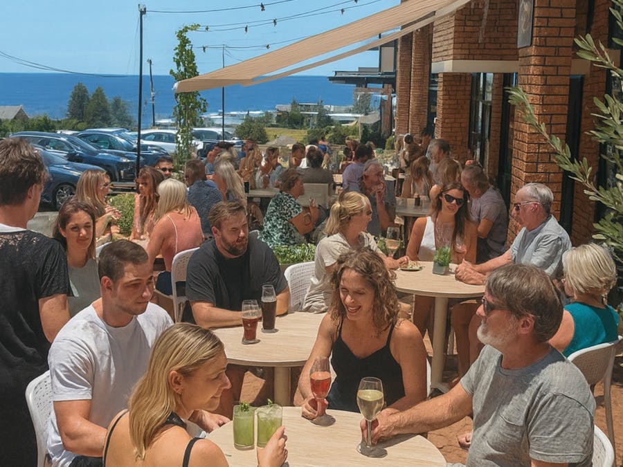 Picture of people eating and drinking outside with ocean views.