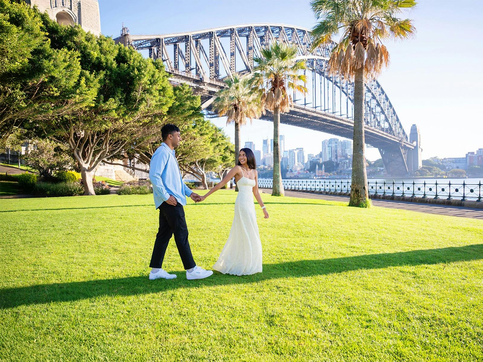Couple walking with Sydney Harbour Bridge during a Sydney Opera & Harbour Portraits session.