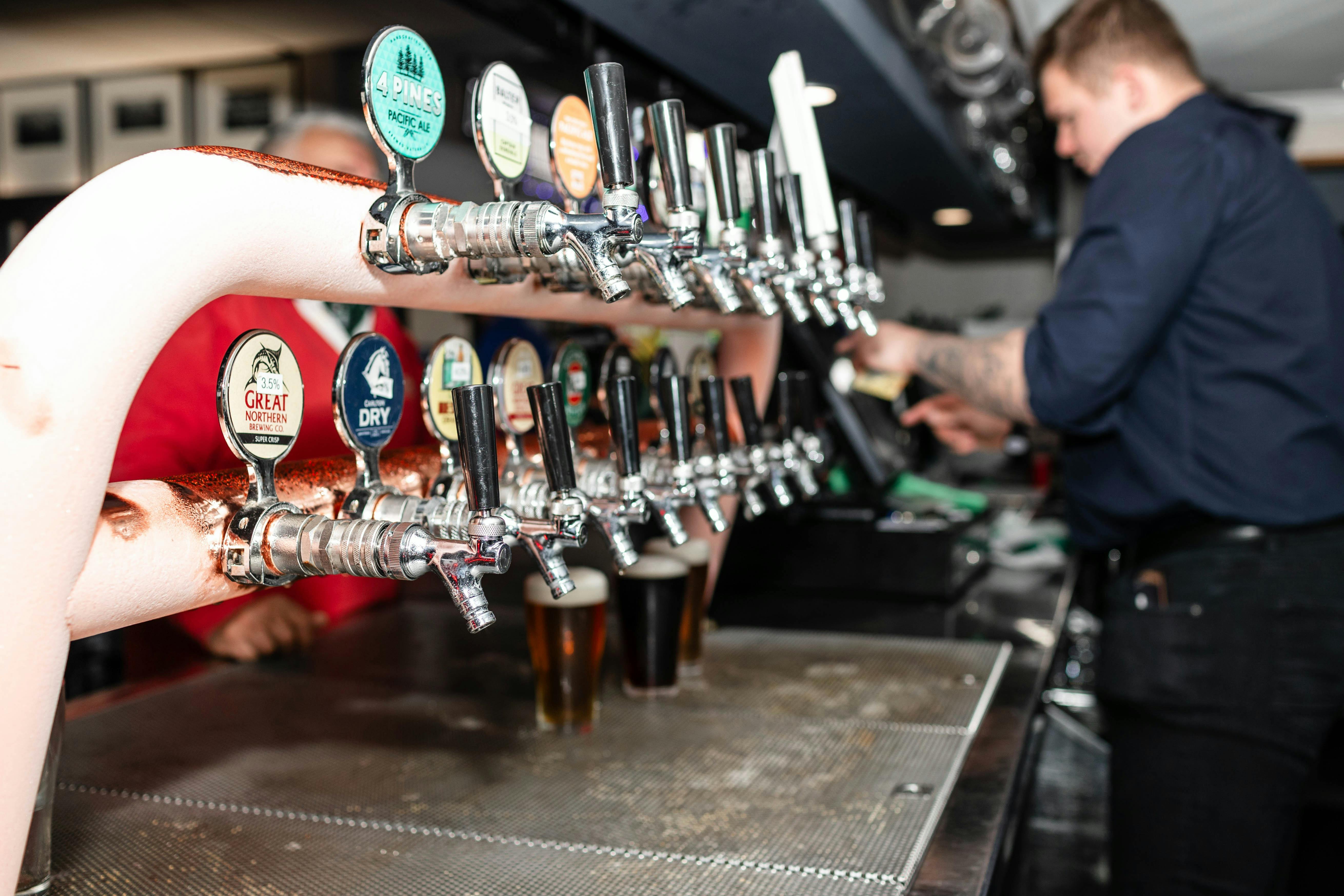 Beer taps in the sports bar, staff pouring beer