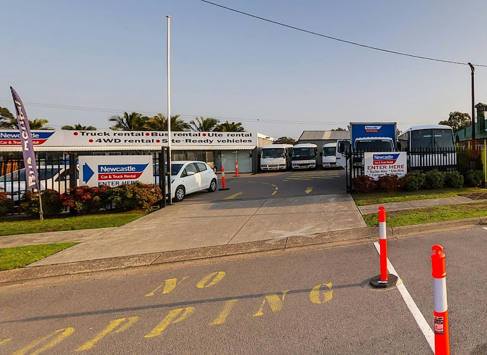 Entrance to Newcastle Car & Truck Rental with rental buses, cars and Enter Here sign