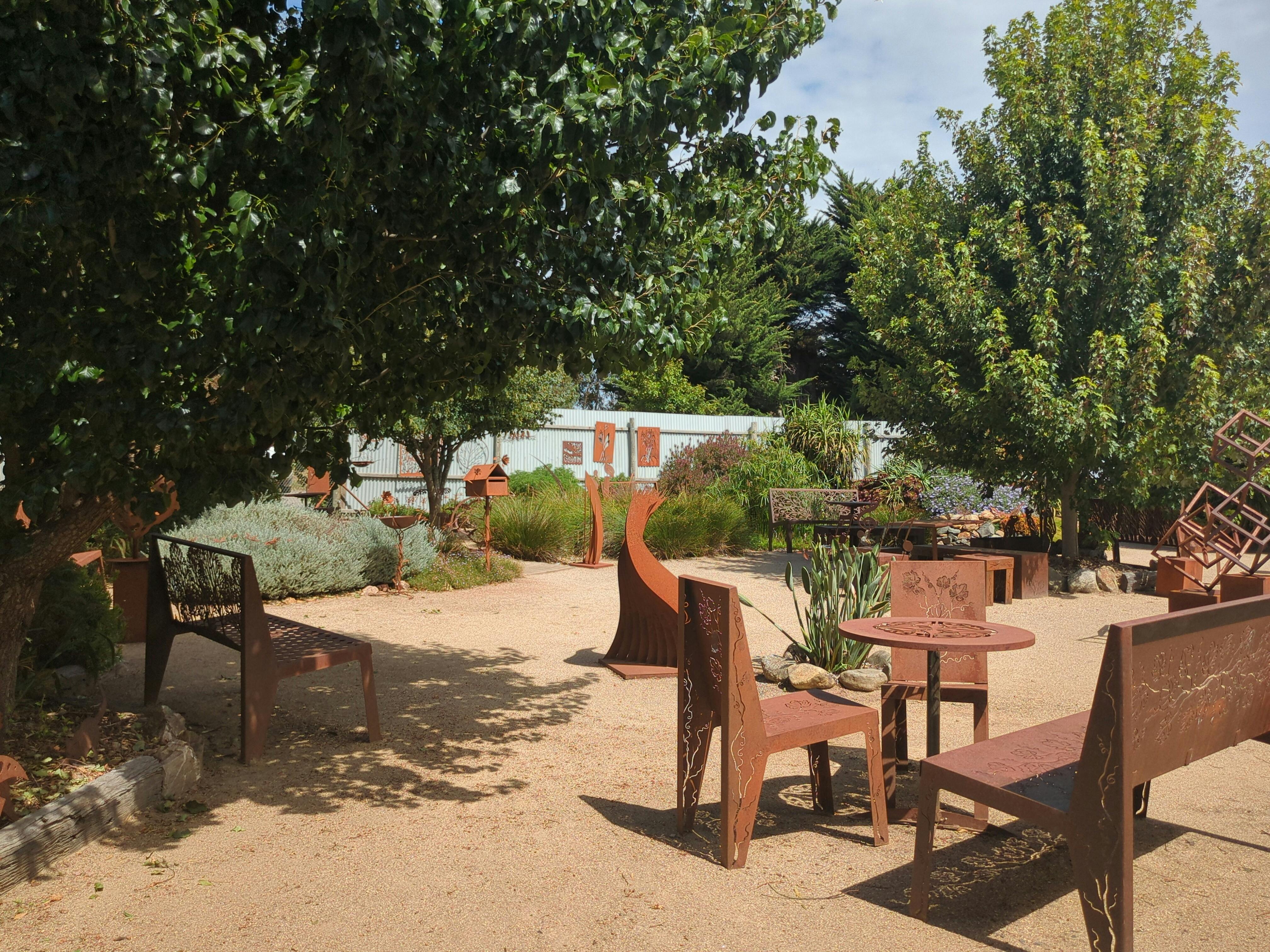 Metal garden seats and benches around a table in the garden.