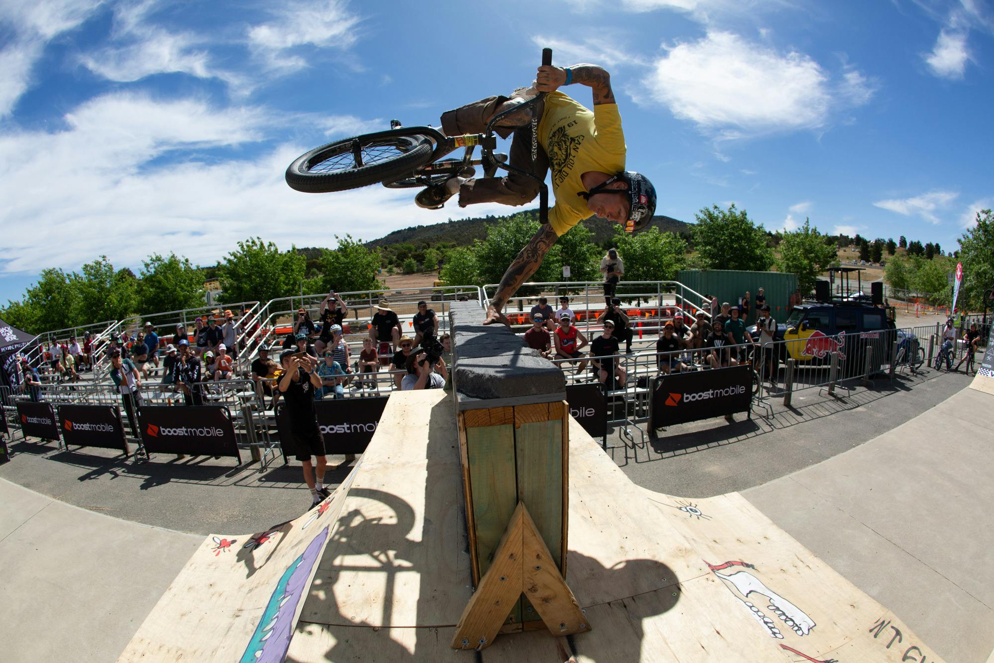 Jon Mackellar riding BMX doing a handplant over a hitching post wall at ACT JAM 2023